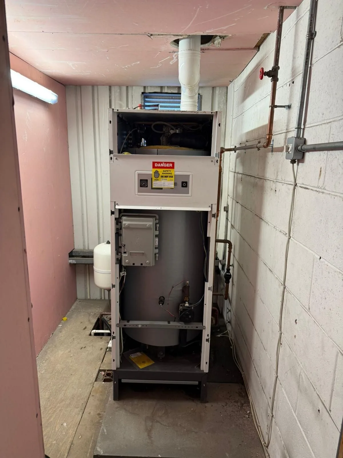 The old gas-fired water heater condemned as unsafe with a do not use label